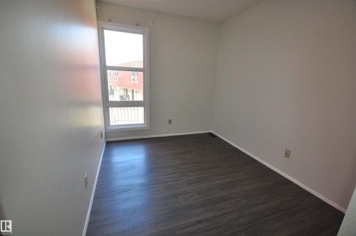 Contemporary room featuring dark wood-finish flooring, light neutral wall paint, and a large multi-pane window with white trim - 617 Millbourne Road E, Edmonton, AB 