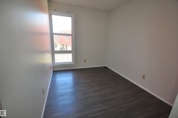 Contemporary room featuring dark wood-finish flooring, light neutral wall paint, and a large multi-pane window with white trim - 