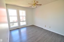 Room featuring wood-finish flooring, white baseboards, and a brass-finish ceiling fan with integrated lighting - 