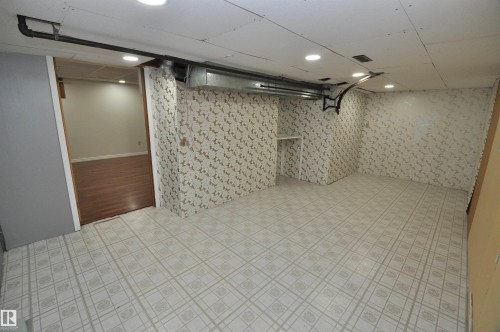 Spacious interior room featuring patterned tile flooring, patterned wall finishes, recessed ceiling lighting, and a built-in shelf - 617 Millbourne Road E, Edmonton, AB 