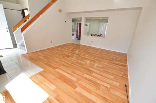 Hardwood flooring with a gloss finish, white tile entry, white baseboards, and a built-in architectural cutout - 617 Millbourne Road E, Edmonton, AB 