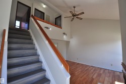 Interior staircase with wood-finish treads and risers, featuring a white railing and natural wood-tone handrail - 