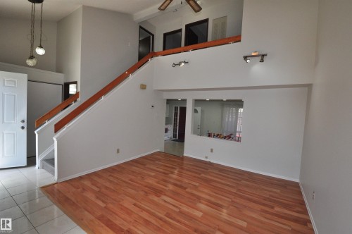 Two-story interior featuring a staircase with a wood handrail, track lighting, and a high ceiling - 617 Millbourne Road E, Edmonton, AB 