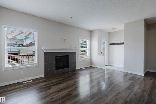 Living area featuring wood-finish flooring, a contemporary fireplace with a gray tiled surround, and a white mantel - 636 Mcdonough Link Link, Edmonton, AB 