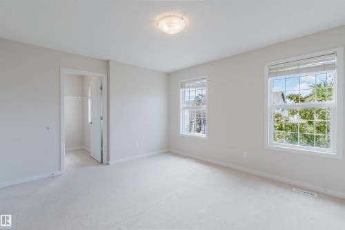 Carpeted room with multiple windows, a ceiling-mounted light fixture, and a closet with bifold doors - 636 Mcdonough Link Link, Edmonton, AB 