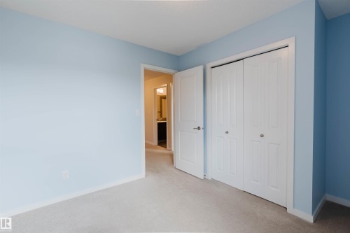 Carpeted room with light blue walls, white bi-fold closet doors, white trim, and a white interior door - 636 Mcdonough Link Link, Edmonton, AB 