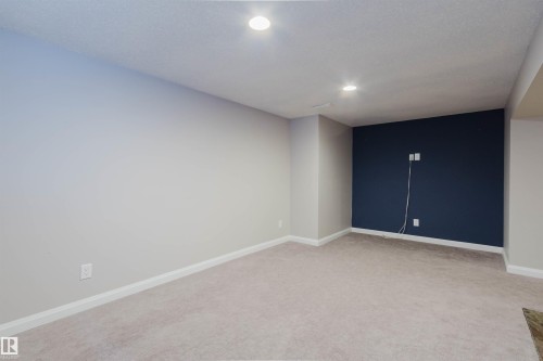 Spacious room featuring neutral carpeting, recessed lighting, white baseboards, and a contrasting accent wall - 636 Mcdonough Link Link, Edmonton, AB 