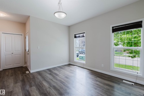 Spacious room featuring wood-finish flooring, two large windows with horizontal blinds, and a contemporary ceiling light fixture - 636 Mcdonough Link Link, Edmonton, AB 
