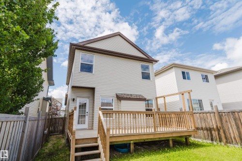 Rear exterior featuring a spacious wood deck with railings, vinyl siding, a glass-paneled back door, and a shingle roof - 636 Mcdonough Link Link, Edmonton, AB 