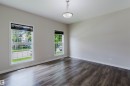 Spacious room featuring wood-finish flooring, light neutral wall paint, white trim, and two large windows with horizontal blinds - 636 Mcdonough Link Link, Edmonton, AB 
