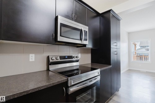 Modern kitchen featuring dark wood-finish cabinetry and stainless steel appliances - 636 Mcdonough Link Link, Edmonton, AB 