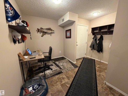 Entryway featuring a built-in coat rack with shelving, a desk area, and a white door - 114 1080 Mcconachie Boulevard, Edmonton, AB 