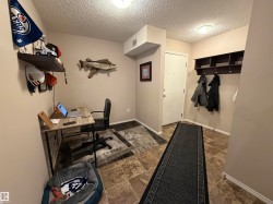 Entryway featuring a built-in coat rack with shelving, a desk area, and a white door - 