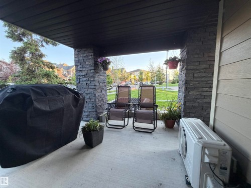 Covered front porch featuring stacked stone columns, a concrete surface, and dark soffit - 114 1080 Mcconachie Boulevard, Edmonton, AB 