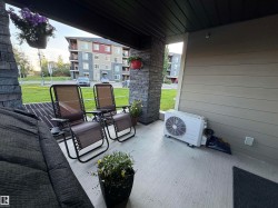 Covered concrete patio featuring stone veneer pillars, horizontal siding, and a slatted ceiling - 