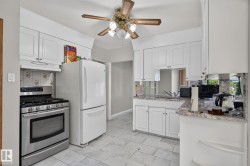 Kitchen featuring white cabinetry, light-toned countertops, tile flooring, and a stainless steel gas range - 