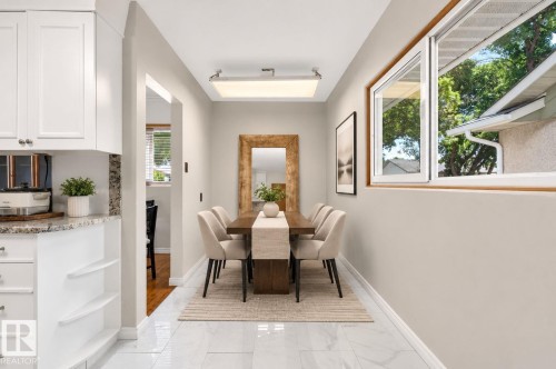 White shaker cabinetry with granite countertops, built-in shelving, and a wood-finish dining table - 12238 48 Street, Edmonton, AB 