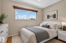 Bedroom featuring a double window with wood blinds, wood-finish flooring, and light neutral wall finishes - 