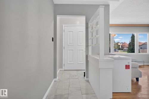 Entryway featuring large format tile flooring, a paneled interior door, and a built-in room divider with shelving - 12238 48 Street, Edmonton, AB 
