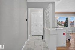 Entryway featuring large format tile flooring, a paneled interior door, and a built-in room divider with shelving - 