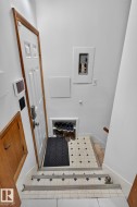 Entryway featuring a white paneled door with wood trim, built-in shoe storage, and tiled flooring - 