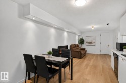 Open-concept living space featuring wood-finish flooring, recessed lighting, a built-in electric fireplace, white cabinetry, and white countertops - 
