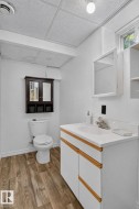 Bathroom featuring a white vanity with wood-finish trim, an integrated sink, and a mirrored medicine cabinet - 