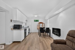 Kitchenette with white cabinetry, light-toned countertops, and black appliances - 