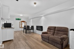 Expansive open-concept room featuring light wood-finish flooring, white walls, and recessed lighting - 