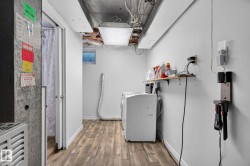 Dedicated utility area featuring wood-finish flooring, white walls, a small window, and a built-in shelf - 