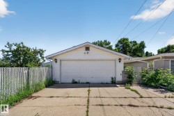 Detached garage featuring white siding, a single overhead door, and two exterior sconce lights - 