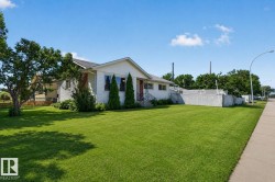 Expansive front yard with a lush green lawn and mature trees - 