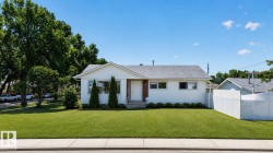 White siding exterior with a dark shingle roof and a vibrant green lawn - 