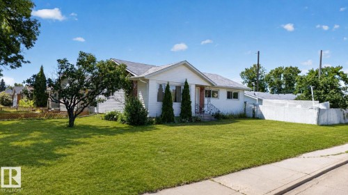 Single-story home featuring white siding, a dark shingle roof, and a prominent front lawn - 12238 48 Street, Edmonton, AB 