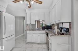 Kitchen featuring white shaker-style cabinetry, granite-look countertops, tiled flooring, and a ceiling fan with integrated lighting - 