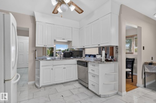 Kitchen featuring white shaker-style cabinetry, granite countertops, and a stainless steel dishwasher - 12238 48 Street, Edmonton, AB 