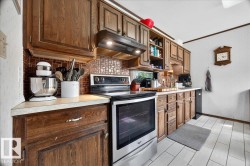 Kitchen featuring wood cabinetry, light countertops, and a patterned tile backsplash - 