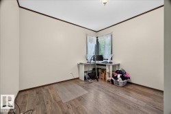 Room featuring wood-finish flooring, neutral wall paint, and dark trim details - 