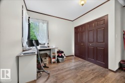 Room featuring wood-finish flooring, white walls, and dark brown trim - 
