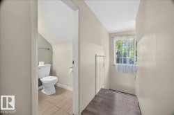 Restroom featuring a white toilet, light-toned wood-finish flooring, and a wall-mounted towel bar - 