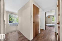 Hallway featuring wood-finish flooring, light-toned walls, and multiple door entries - 