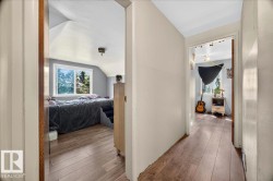 Hardwood-finish flooring extends through the hallway and into a room featuring a window and white trim - 