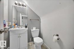 Compact bathroom featuring a white vanity with integrated sink, coordinating toilet, and overhead vanity lighting - 