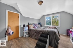 Attic space with sloped ceilings, wood-finish flooring, and a double-pane window - 