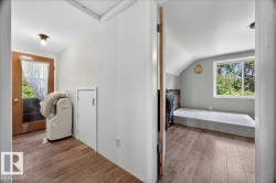 Interior hallway featuring wood-finish flooring, white walls, and a built-in storage cabinet - 