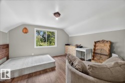 Spacious room featuring wood-finish flooring, a contemporary window, and sloped ceilings - 