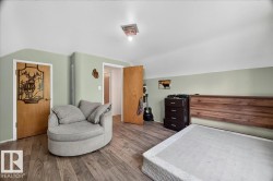 Bedroom featuring wood-finish flooring, a wood headboard, and light green walls with white trim - 