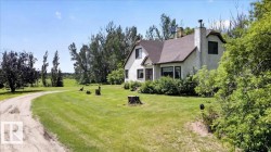 White stucco exterior with a brown shingle roof and a prominent chimney - 