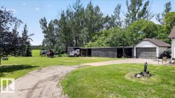 Expansive green lawn with mature trees and a gravel driveway - 