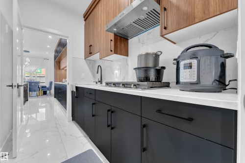 Kitchen featuring two-tone cabinetry with black matte lower cabinets and wood-finish upper cabinets - 16816 49 Street, Edmonton, AB 